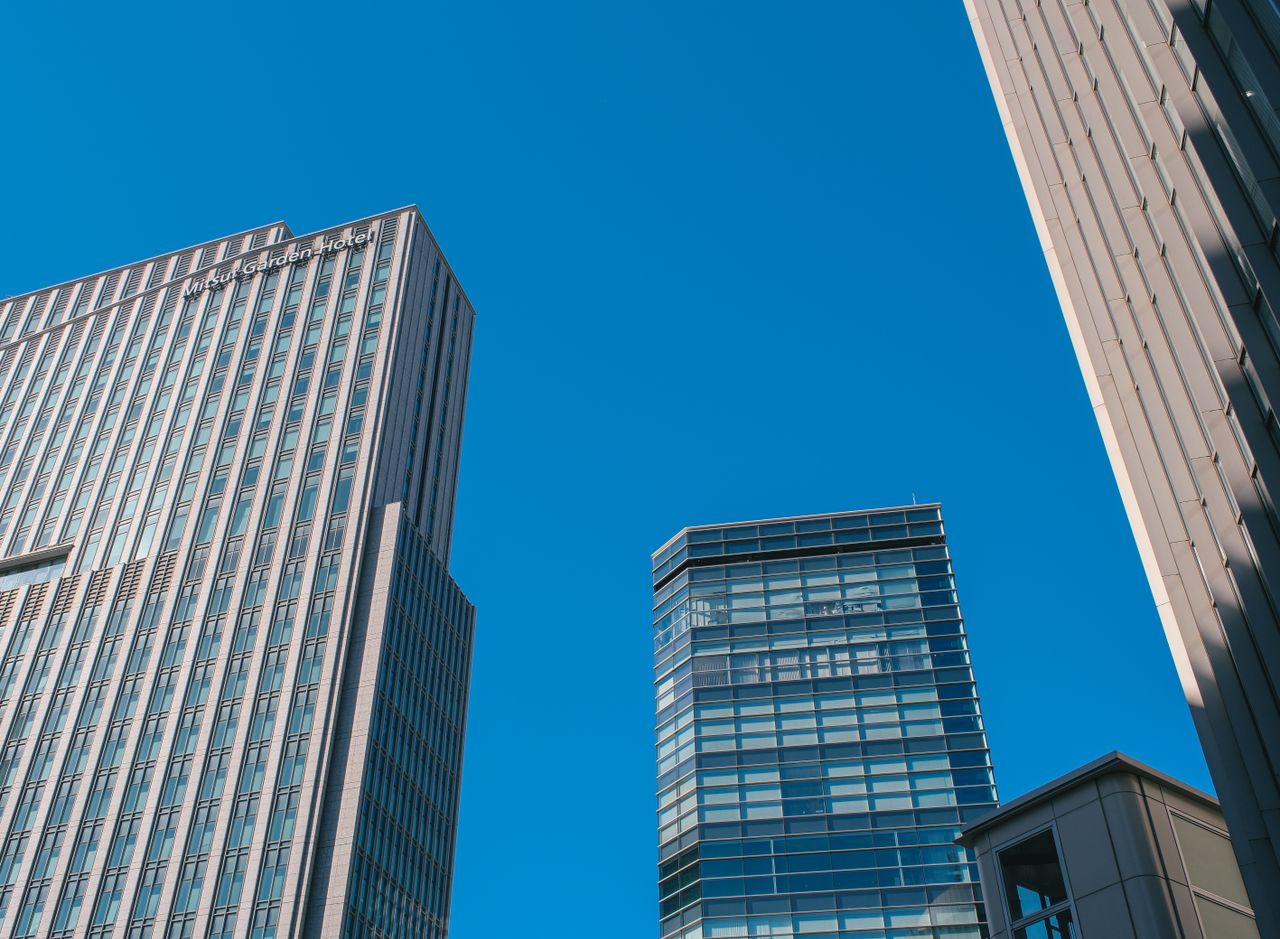 Dynamic view of modern skyscrapers rising against a clear blue sky, showcasing urban architecture.